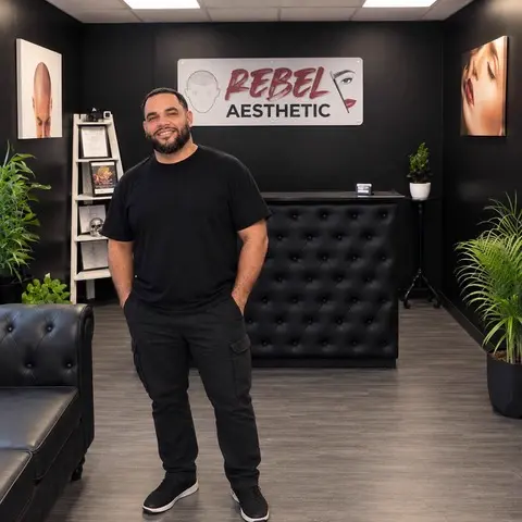Alex Cruz, scalp micropigmentation artist, standing in the Rebel Aesthetic studio in Marlton, NJ