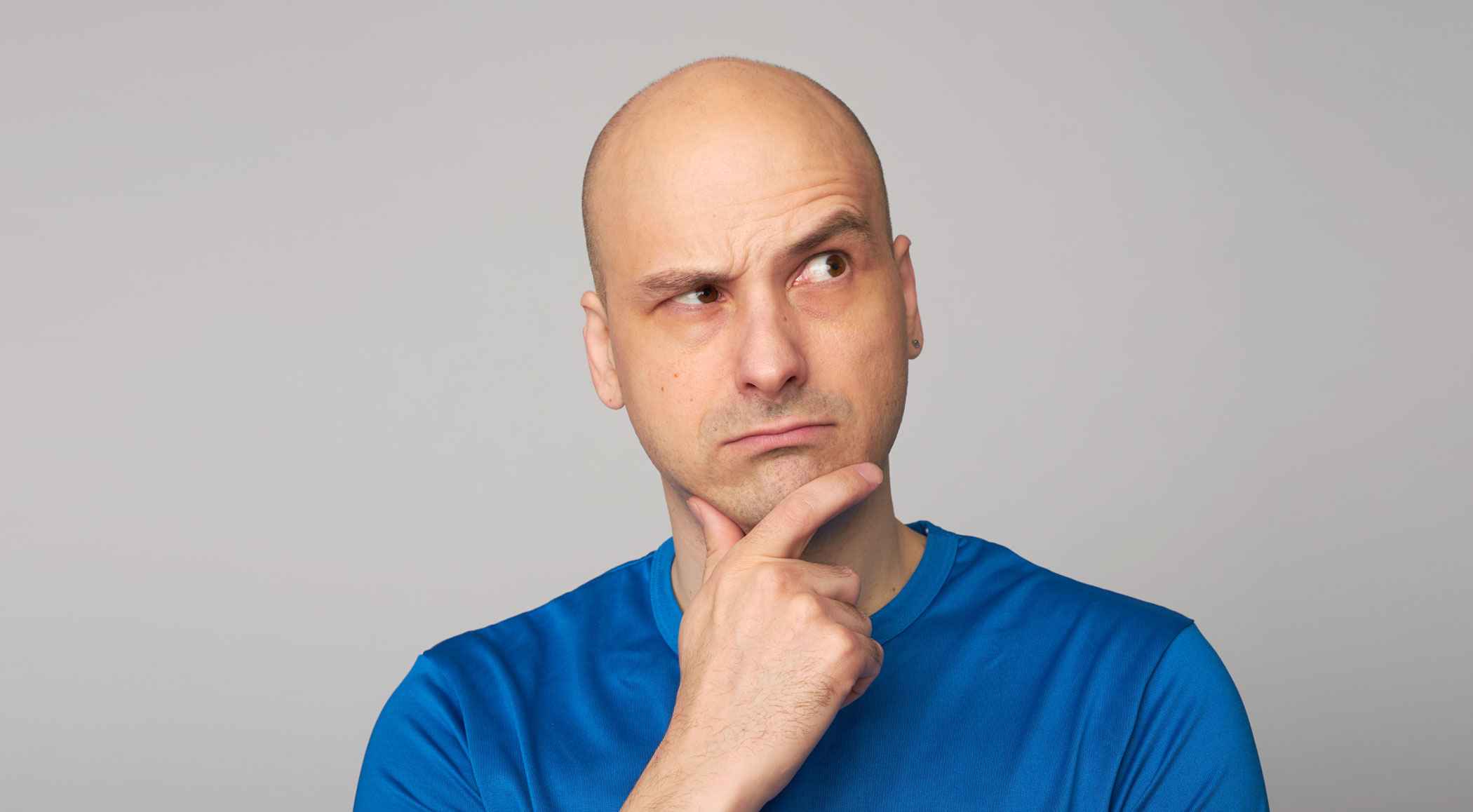 Man with a shaved head thinking about a question